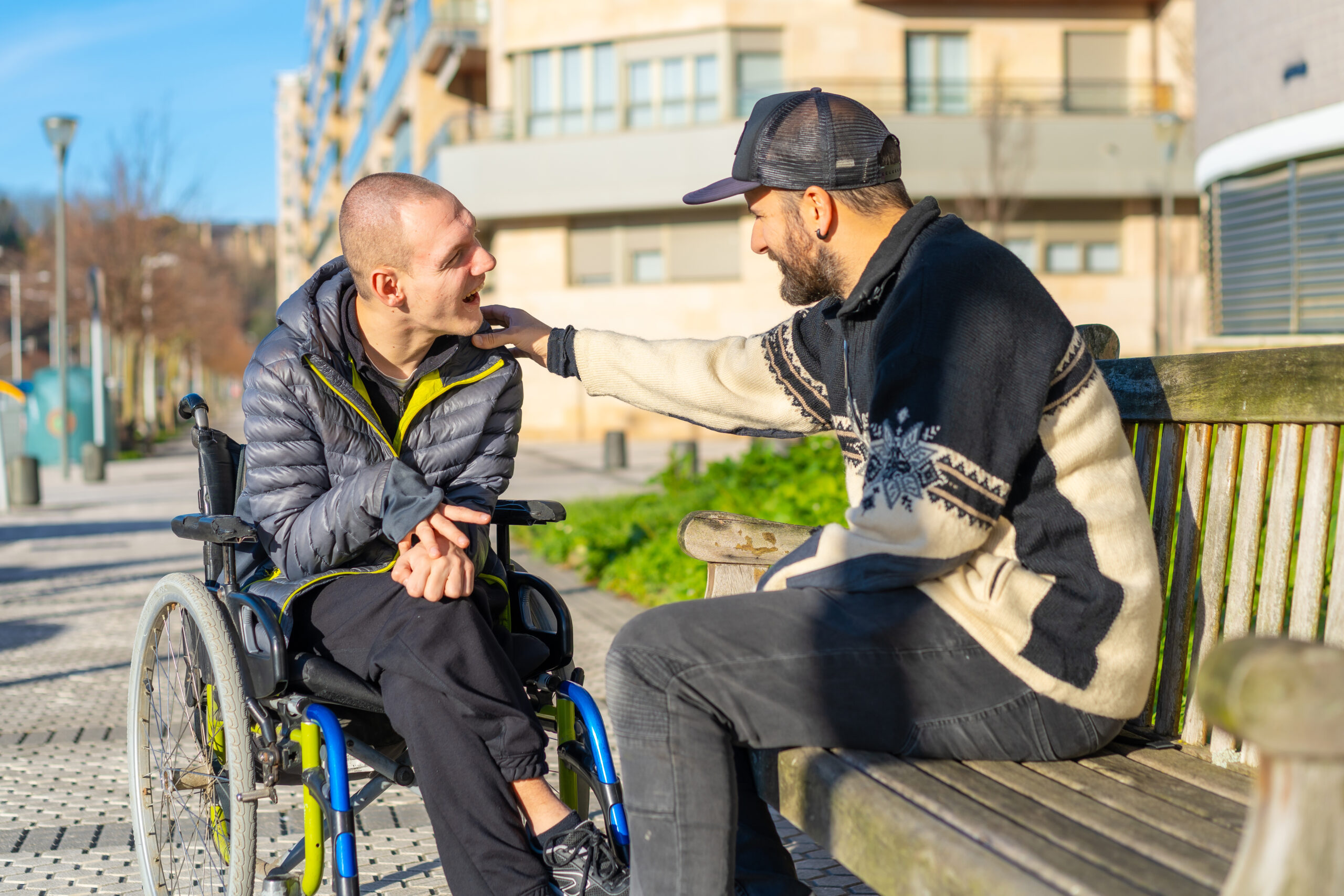 Disabled person in a wheelchair with a friend sitting having fun and talking